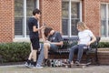 Three teenager boys wearing casual trendy clothes are hanging out in a city park on a sunny day. Royalty Free Stock Photo