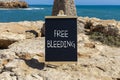 Free bleeding symbol. Concept words Free bleeding on beautiful black chalk blackboard. Beautiful stone sea blue sky background.