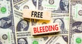 Free bleeding symbol. Concept words Free bleeding on beautiful wooden block. Beautiful background from dollar bills. Dollar bills