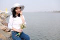 Free careless causual beauty enjoy good time next to a lake ocean river beach hold a bunch of flower wear a hat sit on a rock Royalty Free Stock Photo