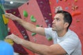 Free climber young man climbing artificial boulder in gym