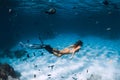 Free diver woman with fins glides over sandy bottom with fishes in transparent sea Royalty Free Stock Photo