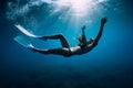 Free diver woman with white fins glides underwater with amazing sun rays. Freediving underwater in sea Royalty Free Stock Photo