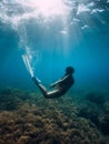 Free diver woman with white fins glides underwater with amazing sun rays. Freediving underwater in sea Royalty Free Stock Photo