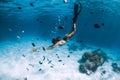 Freediver young woman with fins glides over sandy bottom with tropical fishes in transparent ocean Royalty Free Stock Photo