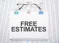 FREE ESTIMATES text written on paper with pen and glasses