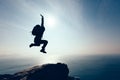 hiker jumping on sunrise seaside cliff edge