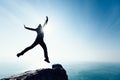 Hiker jumping on sunrise seaside cliff edge Royalty Free Stock Photo