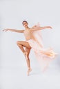 Free flight. Graceful classic ballerina dancing on white studio background. Pastel beige dress cloth. The grace, artist, movement