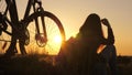 Free girl travels with a bicycle in sunset. Healthy young woman hiker sitting on hill next to bicycle, enjoying nature Royalty Free Stock Photo