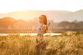 Free happy woman enjoying sunset. Beautiful woman in white dress embracing the golden sunshine glow of sunset with arms outspread Royalty Free Stock Photo