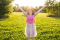 Free happy young woman raising arms watching the sun in the background at sunrise Royalty Free Stock Photo