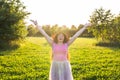 Free happy young woman raising arms watching the sun in the background at sunrise Royalty Free Stock Photo