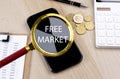 FREE MARKET text on the magnifier with smartphone, calculator and coins Royalty Free Stock Photo