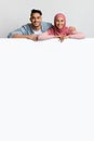 Free Place For Ad. Happy Muslim Couple Leaning At White Advertisement Board Royalty Free Stock Photo