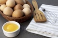 Free-range chicken eggs in a wicker basket. Broken egg, egg yolk. A wooden spatula, and a whisk. Royalty Free Stock Photo