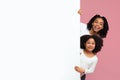 Cheerful Black Mom And Daughter Peeking Out Behind White Advertisement Board Royalty Free Stock Photo