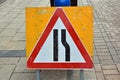 Road narrowing on right sign in red warning triangle on yellow board