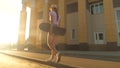 Free teenage girl go with a skateboard in her hands on the street in the city. happy skateboarder travels on the road