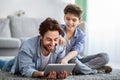 Free time together. Father and son playing online on digital tablet, boy pointing finger to screen Royalty Free Stock Photo