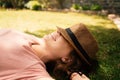 Free woman enjoying nature lying on grass with hat on face. Summer sunny day Royalty Free Stock Photo