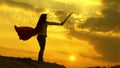 Free woman playing a superhero. super woman with a sword in his hand and in a red cloak stands on a mountain in the