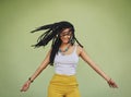 Free your hair and your heart will follow. an attractive young woman dancing against a green background.