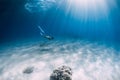 Freediver girl glides over sandy sea with white fins. Freediving with attractive woman in clear ocean