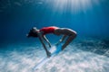 Freediver girl glides over sandy sea with white fins. Freediving with attractive woman in clear ocean