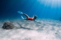 Freediver girl glides over sandy sea with white fins. Freediving with attractive woman in clear ocean