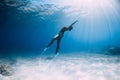 Freediver girl glides over sandy sea with white fins. Freediving with attractive woman in clear ocean