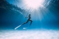 Freediver girl glides over sandy sea with white fins. Freediving with attractive woman in clear ocean