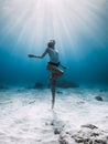 Freediver girl posing underwater. Free diving with woman in blue ocean with sandy bottom and sun rays Royalty Free Stock Photo