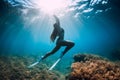 Freediver girl with white fins glides underwater with amazing sun rays and seaweed. Free diving underwater in blue sea Royalty Free Stock Photo