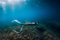 Freediver girl with white fins glides underwater with amazing sun rays and seaweed. Free diving underwater in blue sea Royalty Free Stock Photo