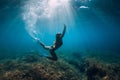 Freediver girl with white fins glides underwater with amazing sun rays and seaweed. Free diving underwater in blue sea Royalty Free Stock Photo