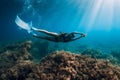 Freediver girl with white fins glides underwater with amazing sun rays and seaweed. Free diving underwater in blue sea Royalty Free Stock Photo