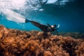 Freediver girl with white fins glides underwater with amazing sun rays and seaweed. Free diving underwater in blue sea Royalty Free Stock Photo