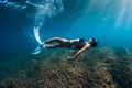 Freediver girl with white fins glides underwater with amazing sun rays and seaweed. Free diving underwater in blue sea Royalty Free Stock Photo