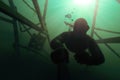 Freediver going deap in the water with a structure above him. Royalty Free Stock Photo
