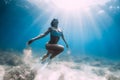 Freediver woman glides and posing over sandy sea with white freediving fins