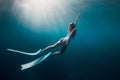 Freediver woman with white fins underwater. Freediving with beautiful girl in ocean and sun rays Royalty Free Stock Photo