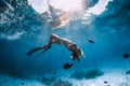 Freediver young woman with fins glides over sandy bottom with tropical fishes in transparent ocean Royalty Free Stock Photo