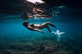 Freediver young woman with white fins glides undersea with sun rays. Freediving in transparent sea