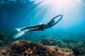 Freediver young woman with white fins glides undersea with sun rays. Freediving in transparent sea