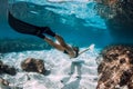 Freediving underwater in blue ocean. Sporty woman freediver swim with fins