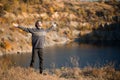 Freedom concept. Free man in sweater and black hat with open arms on sunset admire nature view of autumn lake. success. Travel. Royalty Free Stock Photo