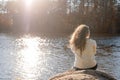 Thoughtful romantic woman sitting on the river bank in sunset in autumn day Royalty Free Stock Photo