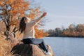 Thoughtful romantic woman sitting on rocks on the river bank in sunset in autumn day Royalty Free Stock Photo