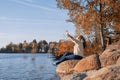 Thoughtful romantic woman sitting on rocks on the river bank in sunset in autumn day Royalty Free Stock Photo